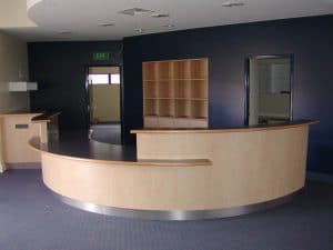 A reception area in an office with curved timber desk